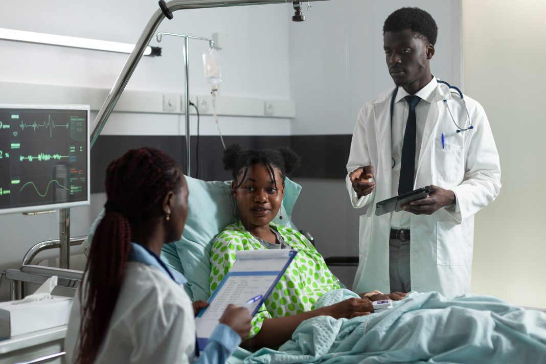 African american man and woman talking to girl in hospital ward